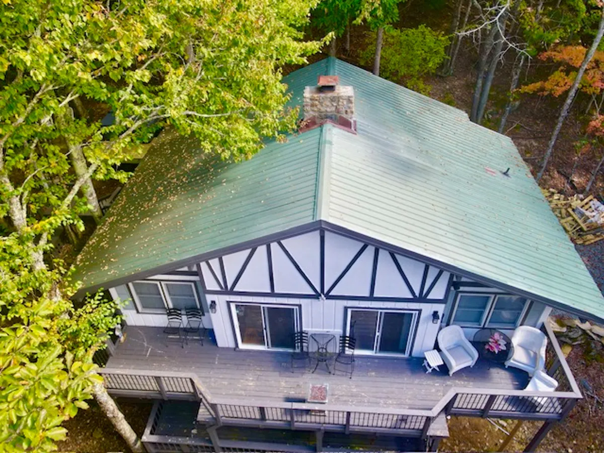 This image features the wooden deck of Wolfman Lodge, surrounded by lush trees and outdoor seating. The green metal roof and the natural environment help set the scene for relaxation and nature immersion. The context suggests a place for sunrise coffee, evening gatherings, or simply soaking up the surrounding forest.