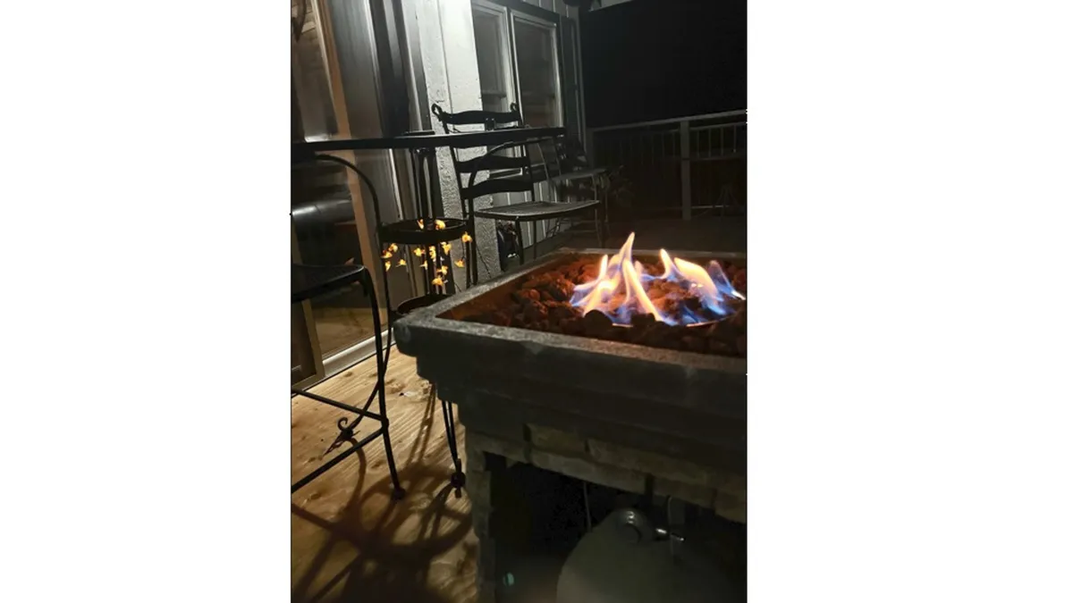 A modern fire pit surrounded by comfortable seating sits on the deck just outside a glass door, inviting guests to gather for evening conversations, warmth, and stargazing under the open sky.