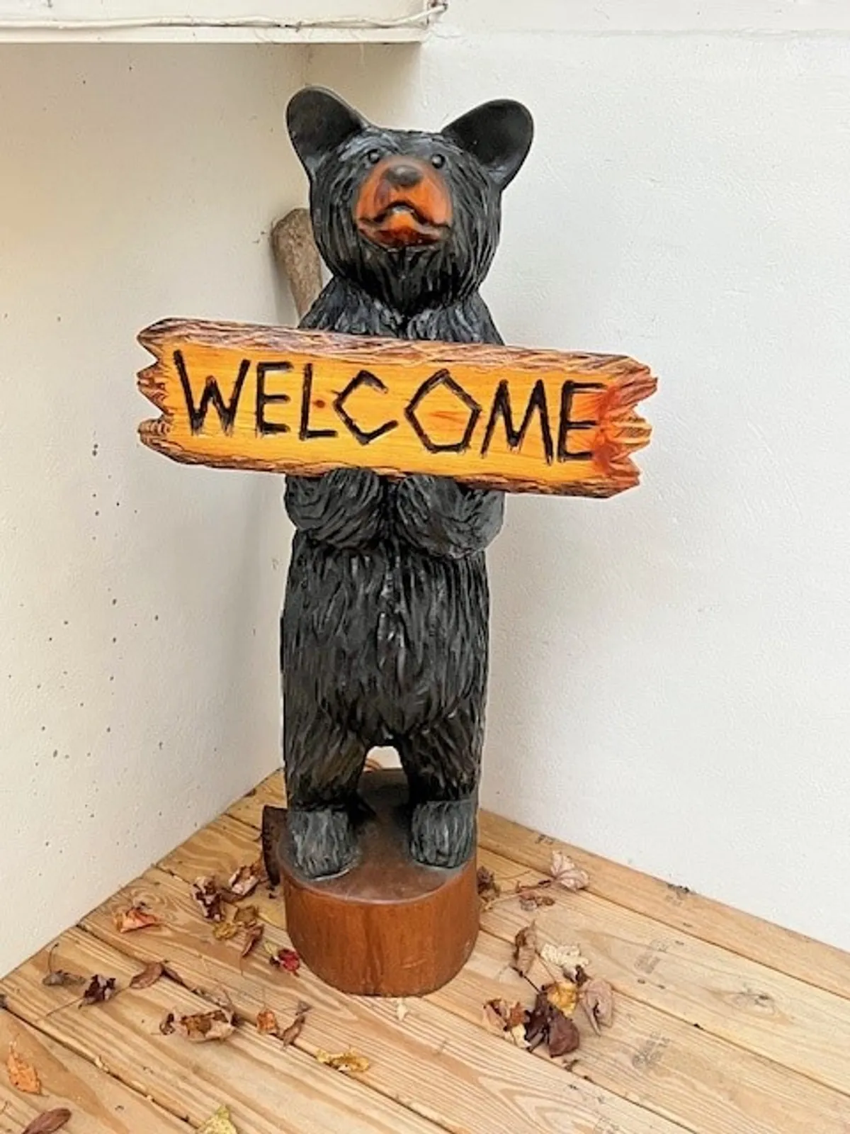 A welcoming entryway featuring a bear statue and a 'welcome' sign, setting a friendly and inviting tone for guests as they arrive at Wolfman Lodge.