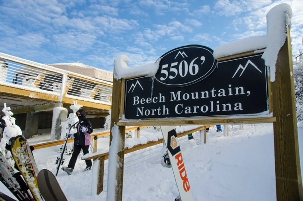 A snow-covered landscape showcasing a sign with elevation and a set of skis leaning against it, with expansive wintry scenery in the background. The crisp snow and high-altitude sign evoke the spirit of mountain sports and alpine adventure.