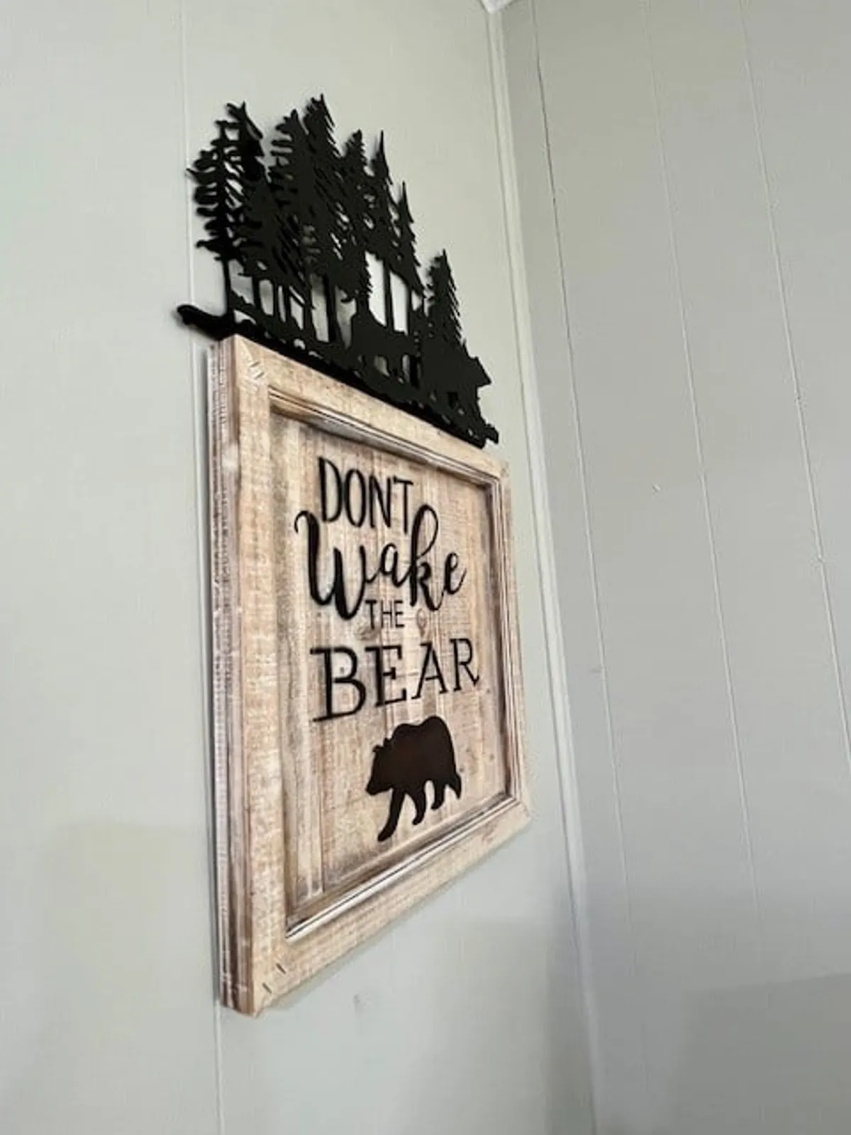 A playful interior sign featuring a bear silhouette and tree cutout, reinforcing the lodge's nature-inspired, pet-friendly atmosphere. The decor hints at cozy evenings and nature-themed storytelling after days filled with outdoor exploration.